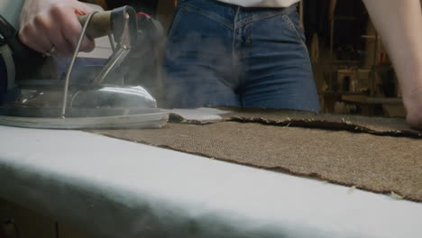 close-up of a person ironing fabric with an industrial steam iron
