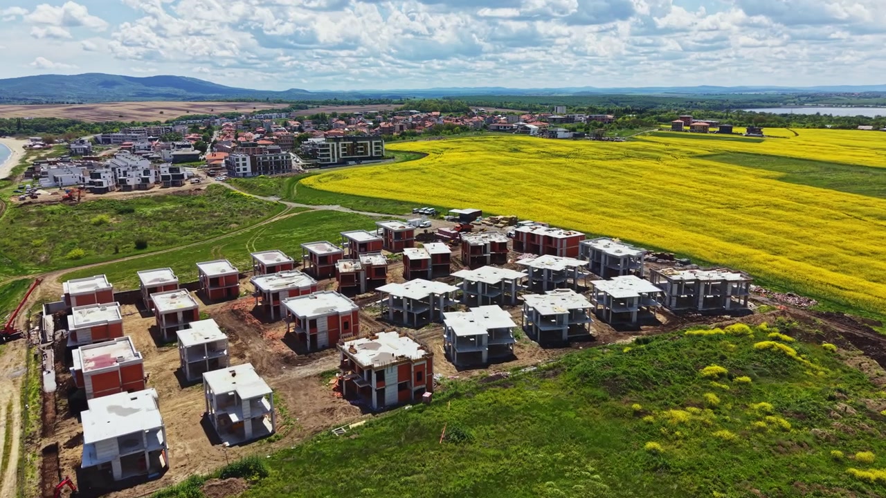 Cantiere edile con nuovi edifici e campi vicino a un paesino in una giornata di sole primaverile