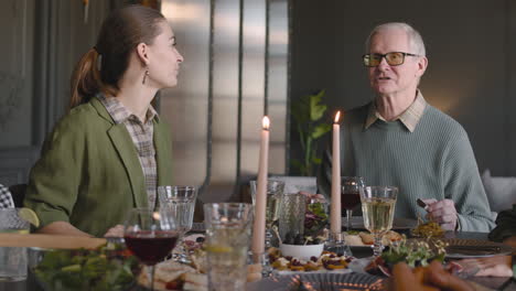 grandfather telling something funny while having meal with his family at home