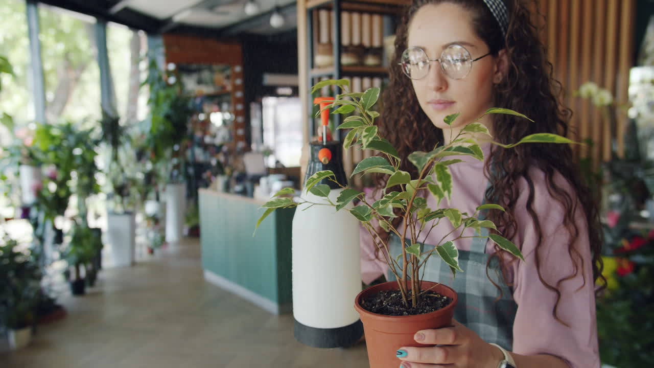 Woman Watering a Plant in a Floral Shop