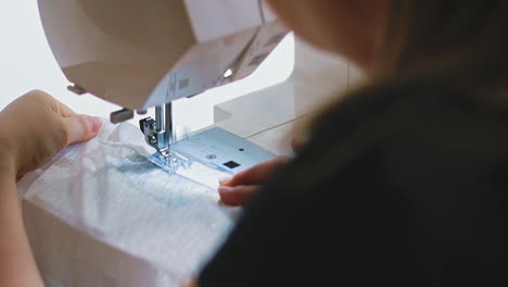 seamstress sews window curtain with machine tool at table