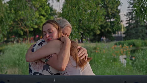 a young woman shares a deep, emotional hug with her mother in a lush public park, radiating love, trust, and warmth at golden hour. left dolley