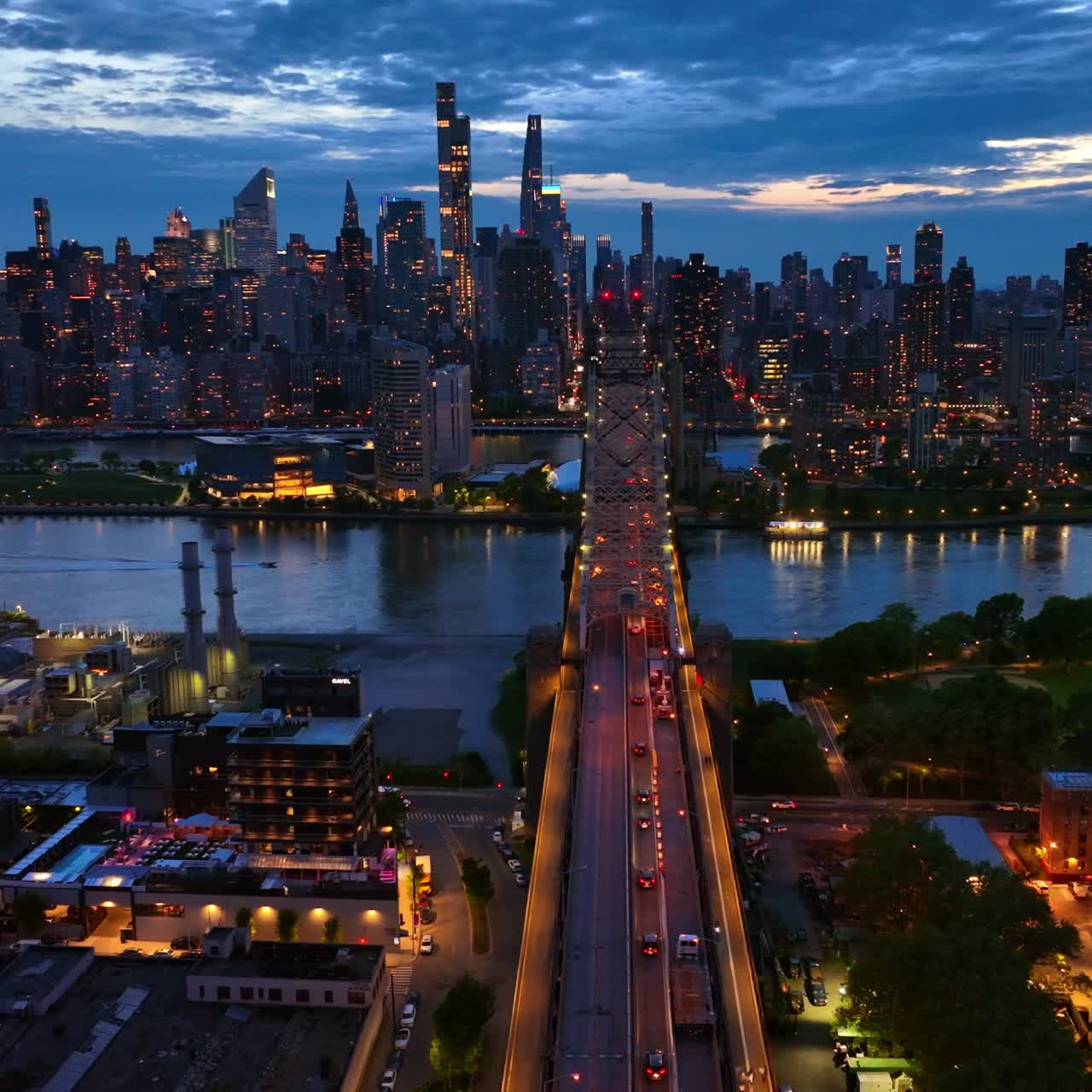 Splendida vista della città al crepuscolo. Queensboro Bridge illuminato con auto di passaggio. Paesaggio urbano con grattacieli sullo sfondo