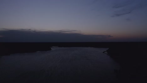 tiro aéreo descendente rodando a través del lago en el crepúsculo