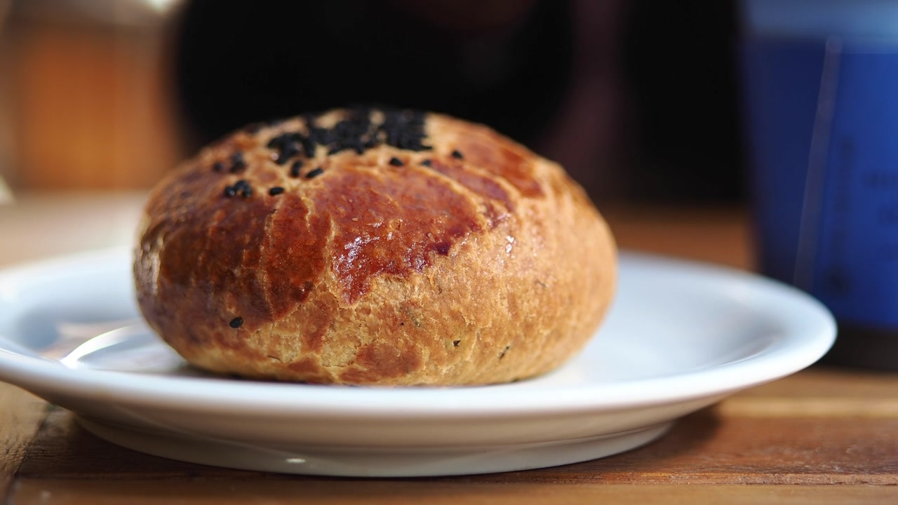 Hand Picking Up Golden Brown Pastry with Black Sesame Seeds