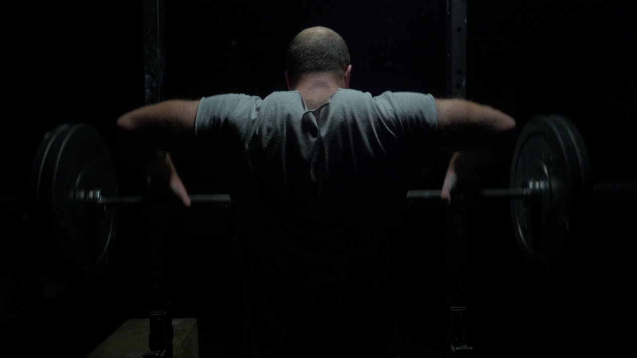Uomo che esegue squat con bilanciere in palestra