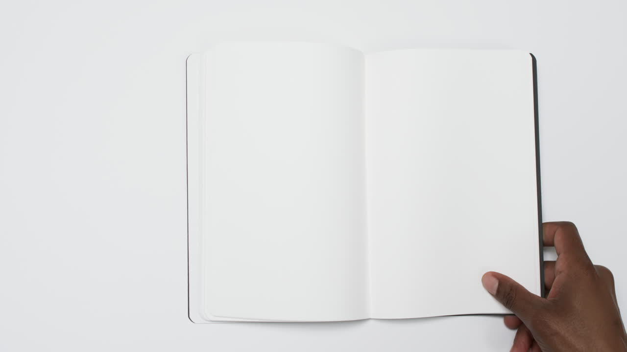 Video of hand of african american man holding book with blank pages, copy space on white background