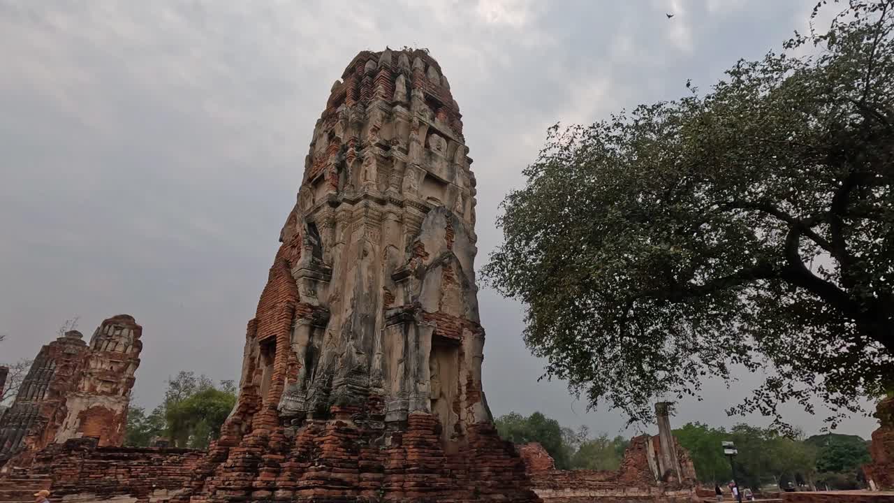 turistas visitando las ruinas históricas del templo bajo un cielo nublado
