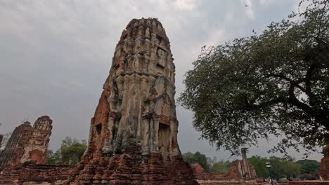 tourists visiting historic temple ruins under cloudy skies