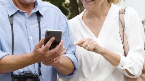 Mittelteil-Des-Touristischen-Paares,-Das-Sich-Die-Karte-Am-Telefon-Ansieht