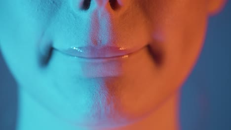 extreme close up of beautiful authentic woman lips pressing or squeezing her lip together after applying her lip gloss while getting ready for the evening with turquoise orange contrast in her face