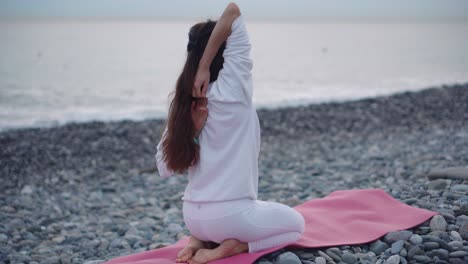 woman practicing yoga on a beach