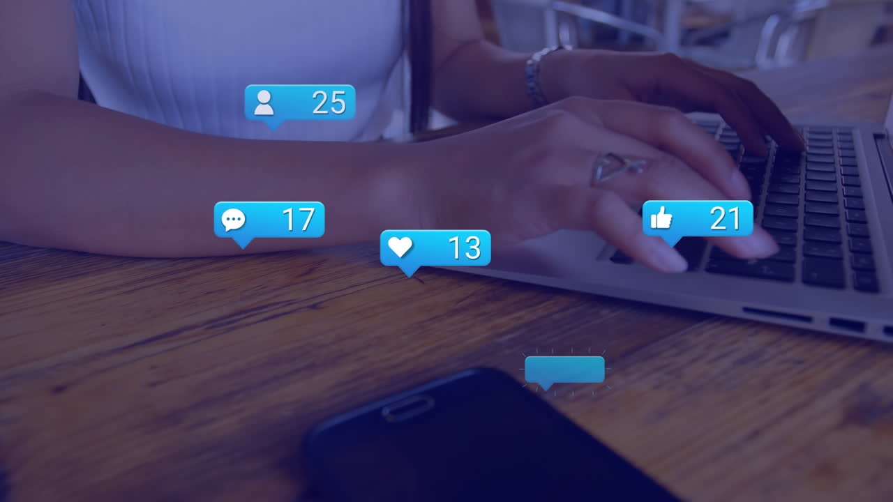 Animation of social media reactions over hands of biracial girl using laptop at school