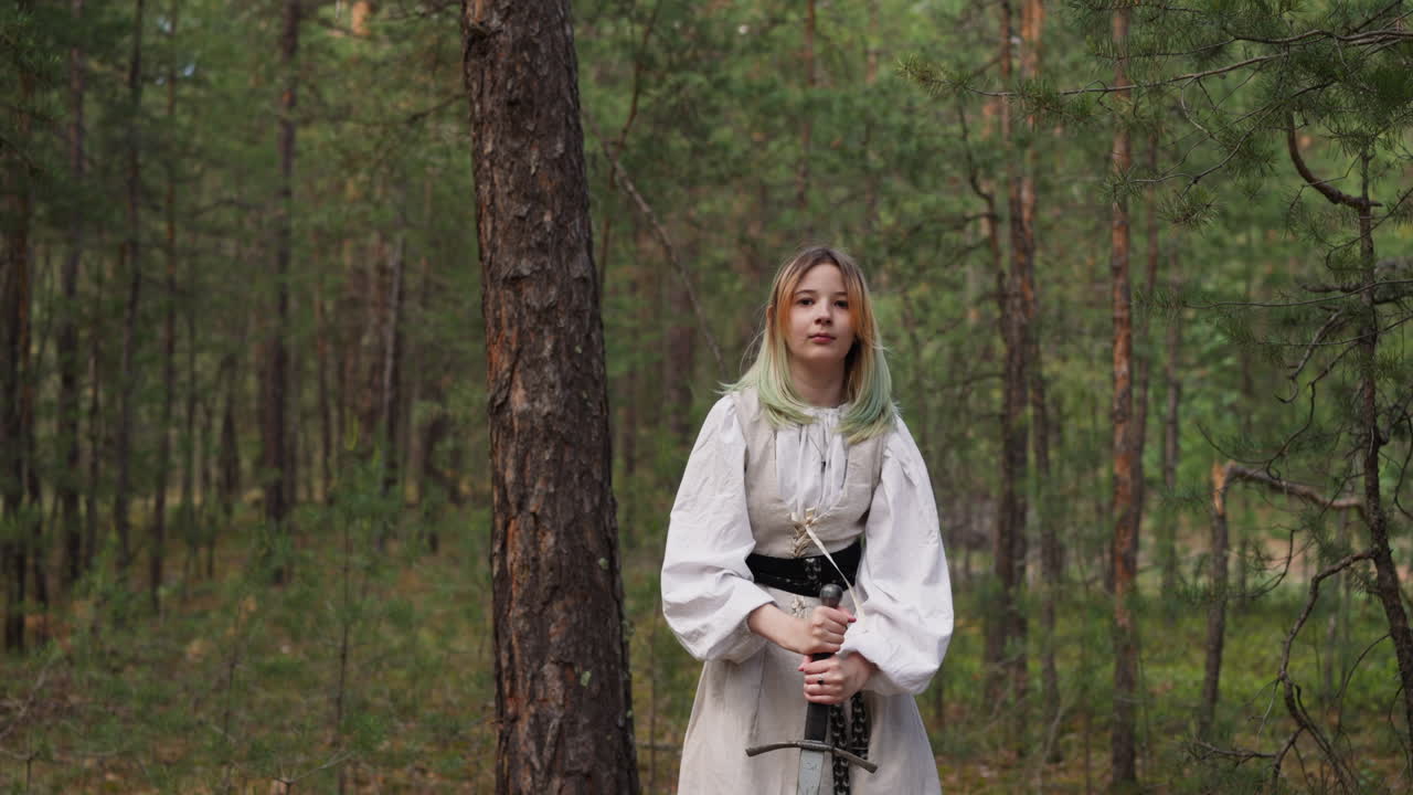 una princesa medieval con un vestido blanco clava una espada en el suelo