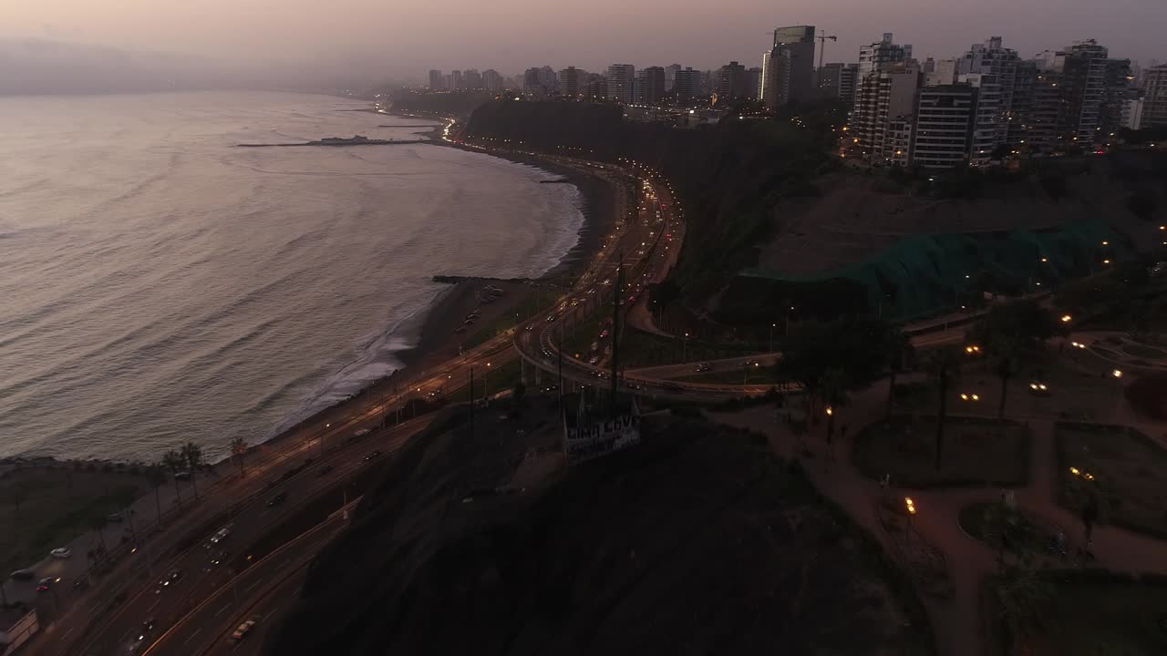 vídeo hyperlape aéreo hecho con un dron sobre el acantilado costero de la ciudad de lima durante un día nublado por la tarde. la carretera por la noche se conoce como "costa verde" junto al océano pacífico en perú.