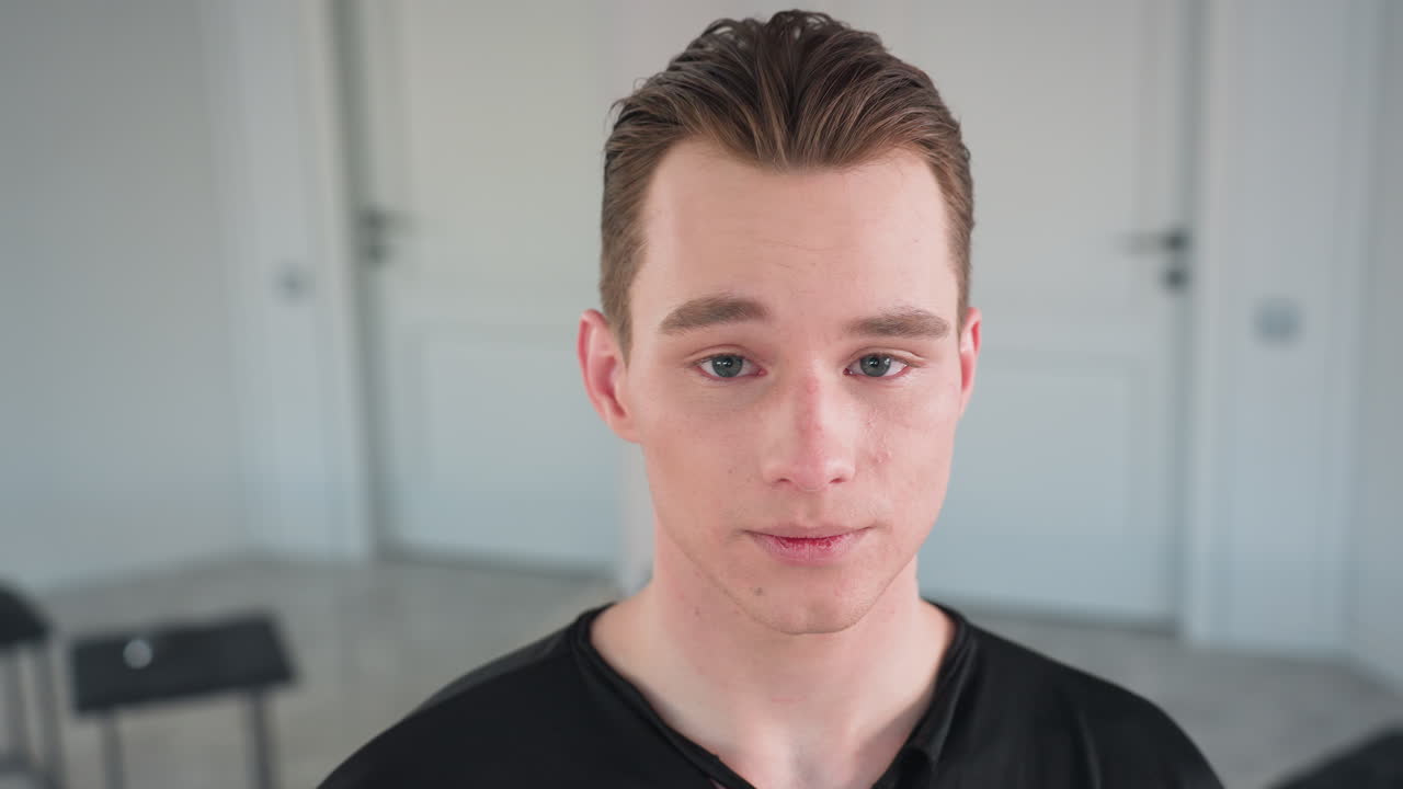 close up of young student in black shirt standing indoors shaking head in clear gesture of disagreement with subtle facial tension and minimalist mirror studio background