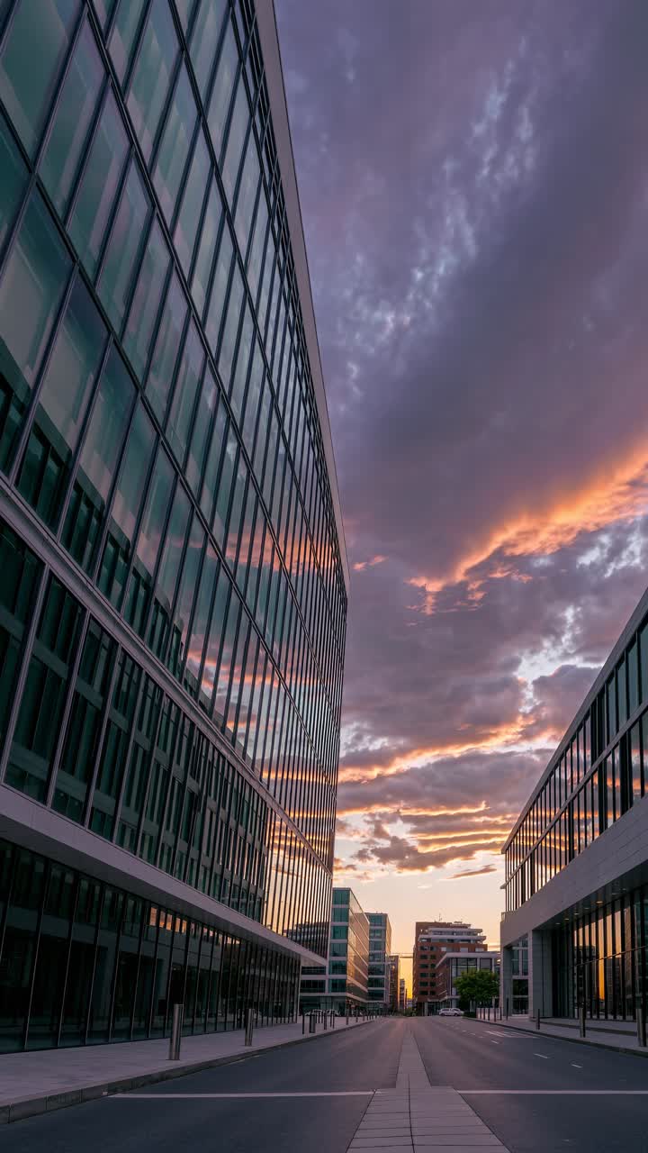Dramatic sunset video scene with a low-angle view of modern glass buildings lining an empty street