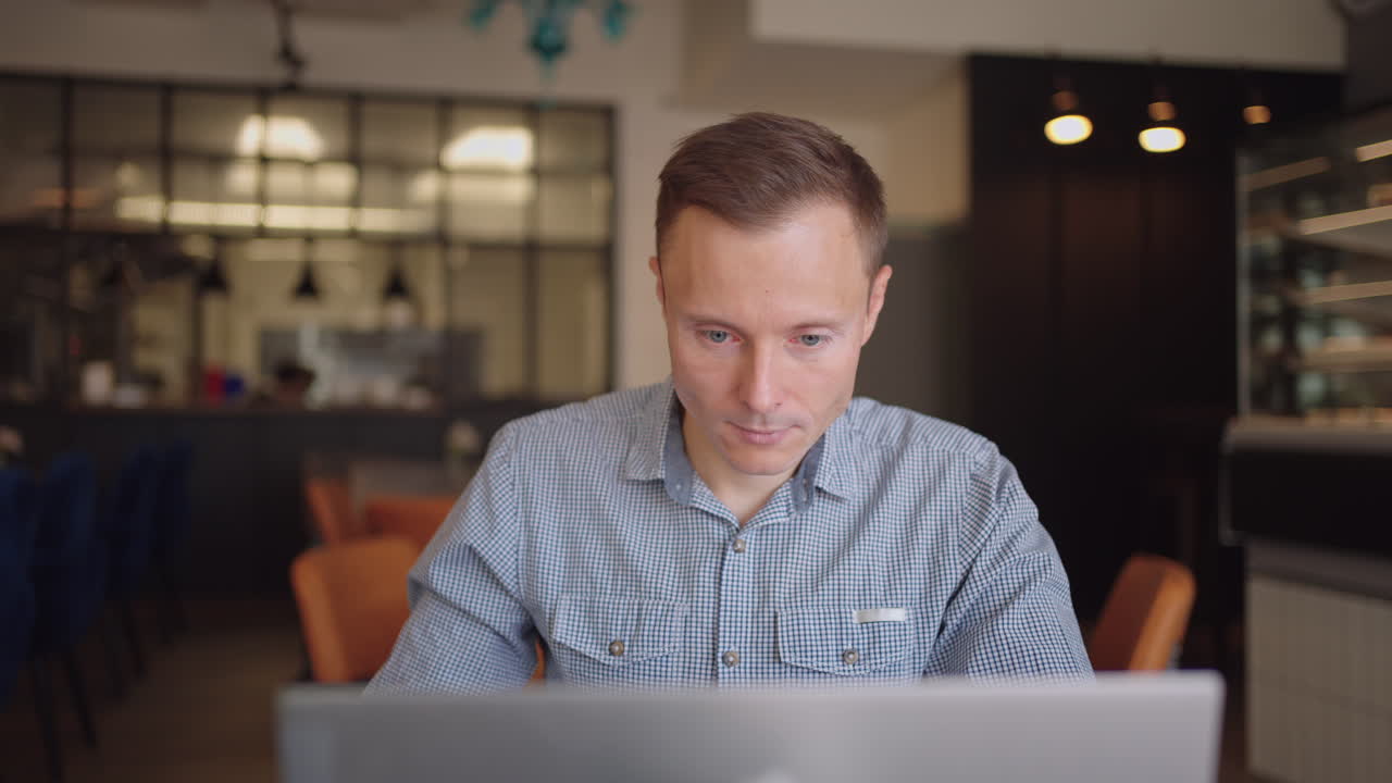 un hombre serio es un estudiante de negocios trabajando estudiando sentado en una mesa y escribiendo un mensaje en una computadora portátil. escribiendo texto en el teclado