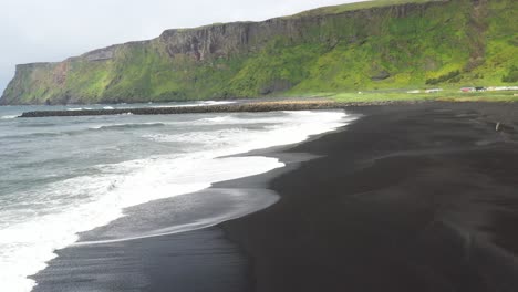 Schwarzer-Sandstrand-Mit-Wellen-In-Vik,-Island-Mit-Drohnenvideo,-Das-Sich-Vorwärts-Bewegt