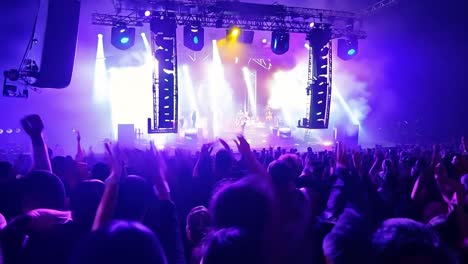 crowd at a concert with hands raised in the air