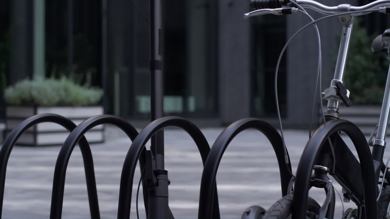 검은색 자전거와 함께 공유 주차장에 서 있는 클로즈업 전기 스쿠터.