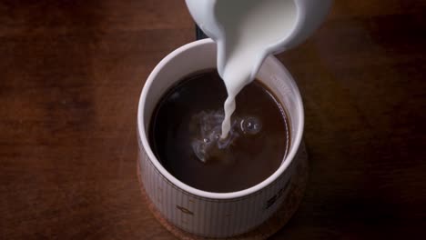 super cámara lenta de crema salpicando en una taza de café caliente