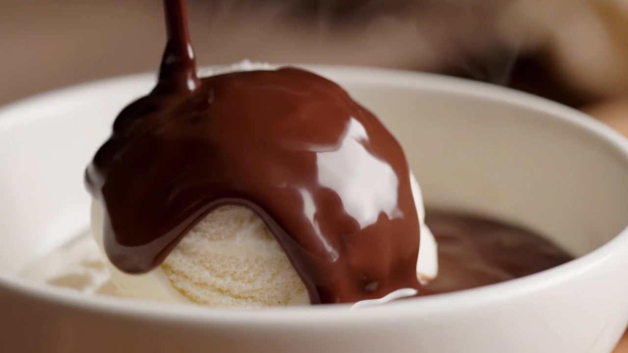 Un'esperienza di dessert sontuosa: un viaggio visivo dal cremoso gelato alla vaniglia a una ricca e lucida salsa al cioccolato che cola dall'alto, perfettamente irresistibile per ogni goloso