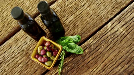 Olive-oil-bottles,-herbs-and-bowl-olives