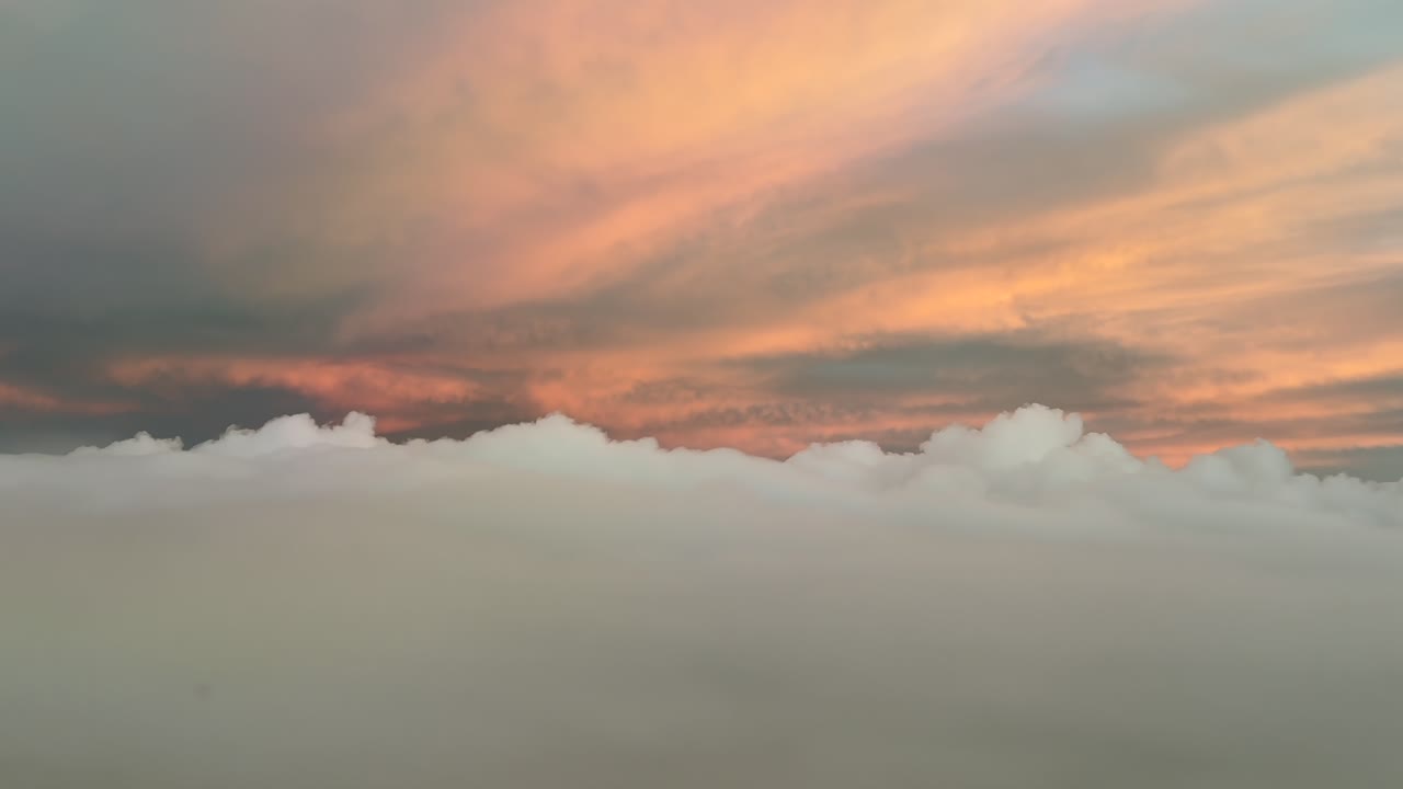 POV flying through a pastel color sky with golden clouds illuminated by sunrise light. A pilot’s perspective taken from the cockpit of a jet .4K 60FPS