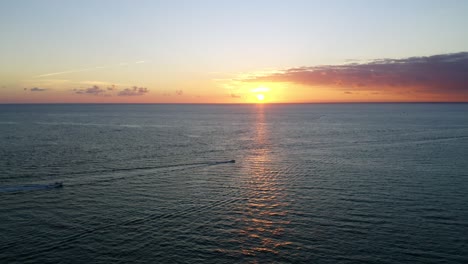 Hermosa-Siguiente-Toma-De-Drone-Del-Amanecer-Sobre-El-Océano-Atlántico-Con-2-Barcos-En-La-Distancia-Dirigiéndose-Al-Mar