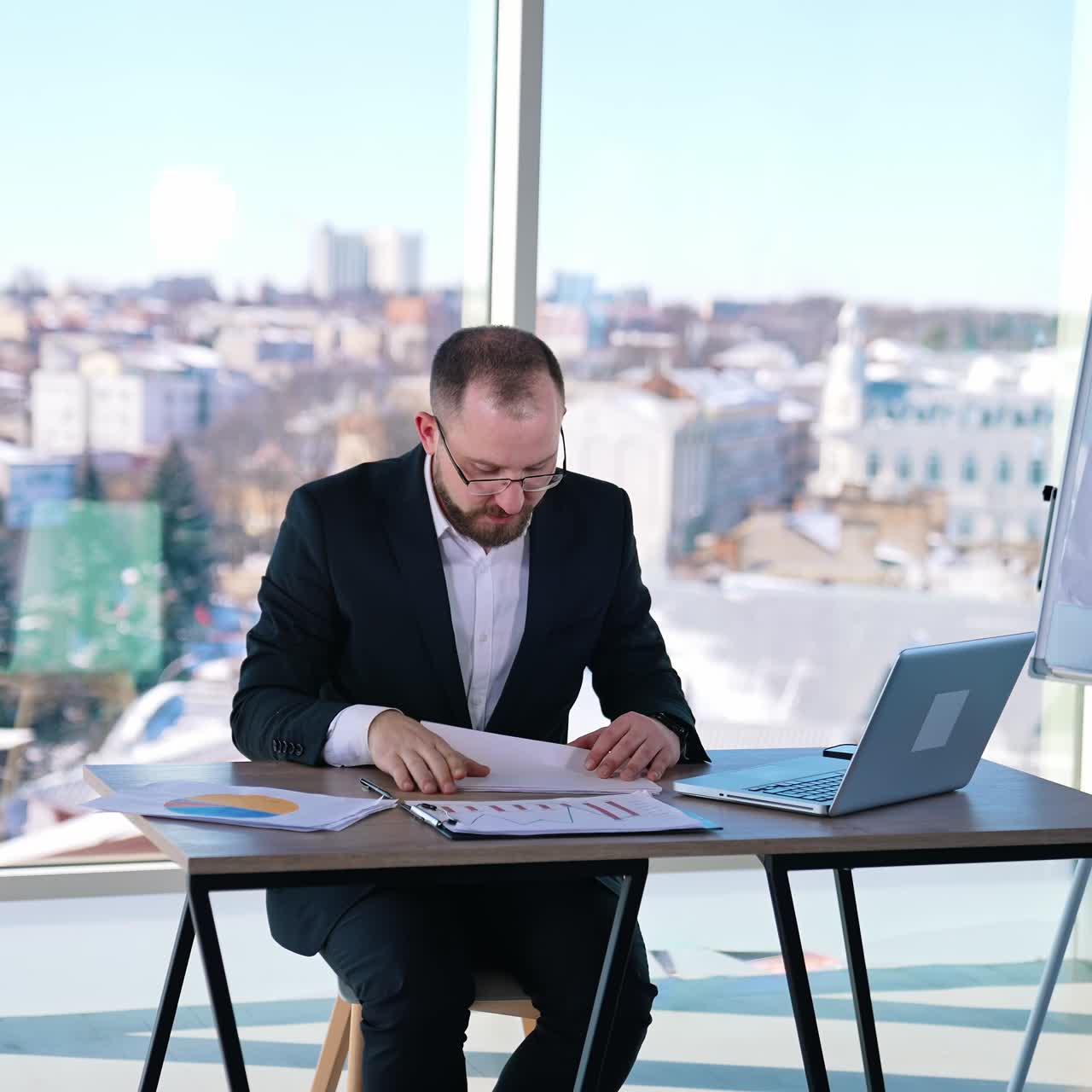 Nervous entrepreneur on his workplace. Businessman in costume sitting at the desk and throwing papers. Business problems