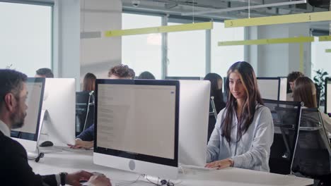 oficina corporativa moderna de espacio abierto con filas de remolque de hombres y mujeres de negocios que trabajan en computadoras de escritorio. oficina de espacio abierto brillante con hombres de negocios y vendedores