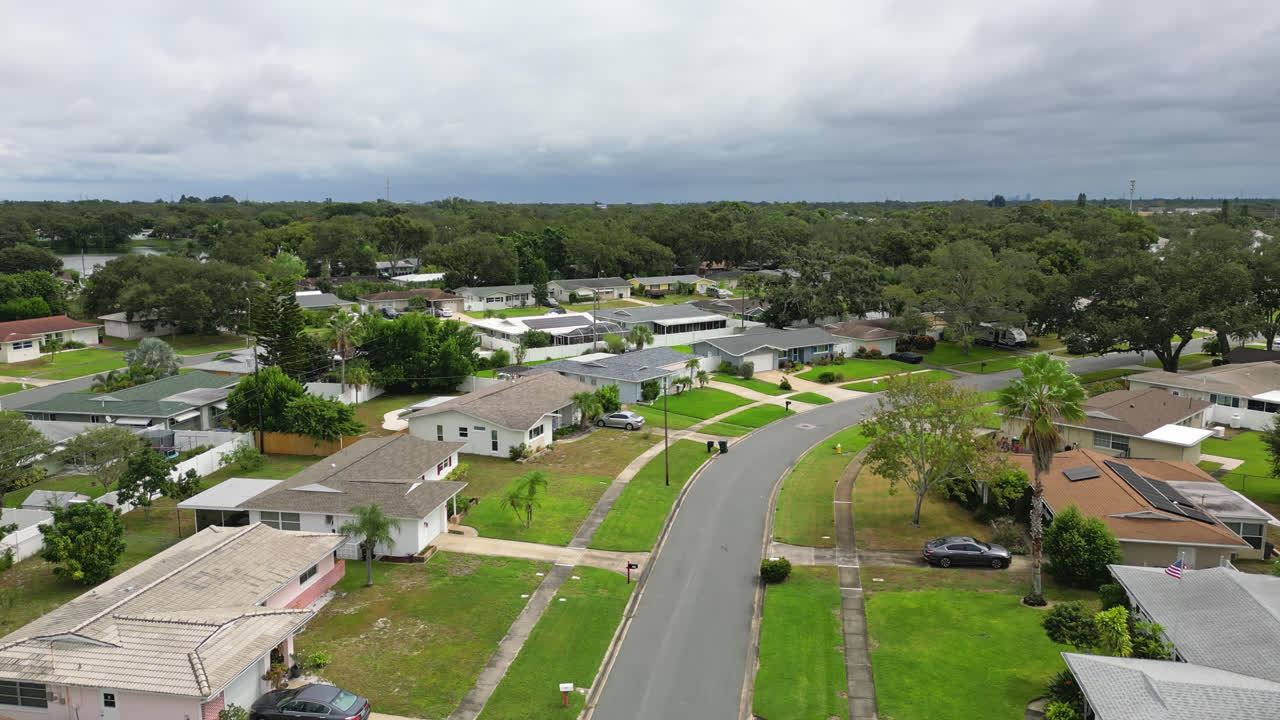Aerial view over a Suburban neighborhood with cut green grass yards and dense trees