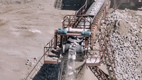 stones cascading down a conveyor belt in a quarry setting