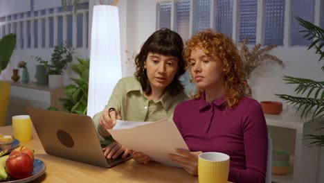 two women working together with a laptop and document