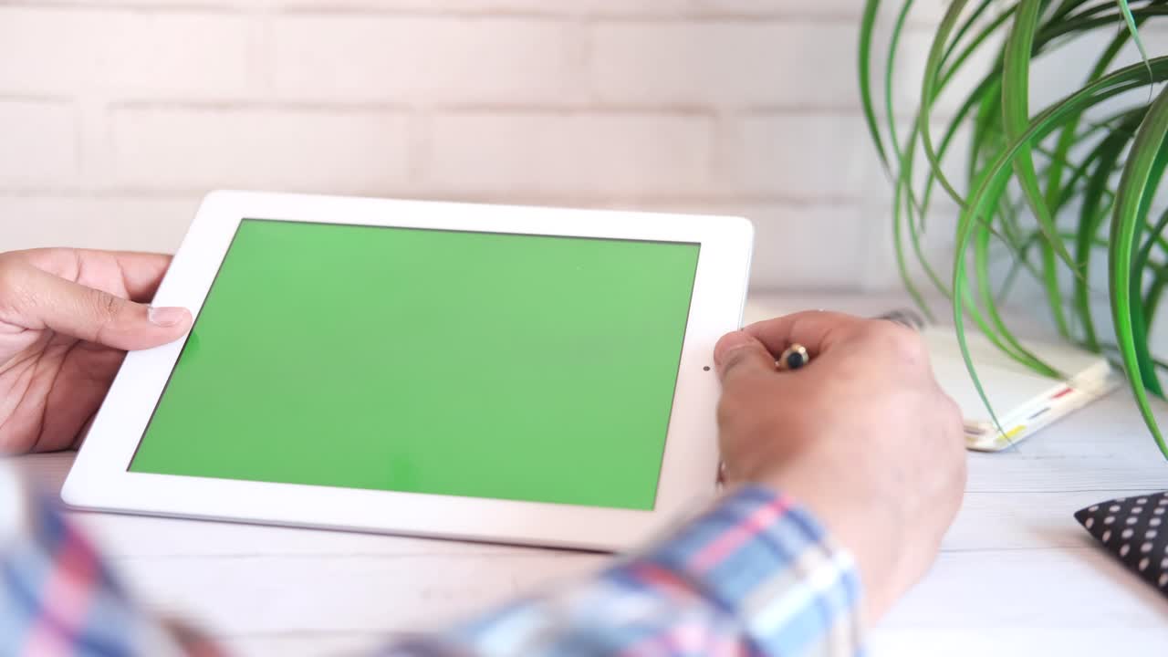 초록색 화면 을 가진 색 태블릿 을 들고 있는 사람