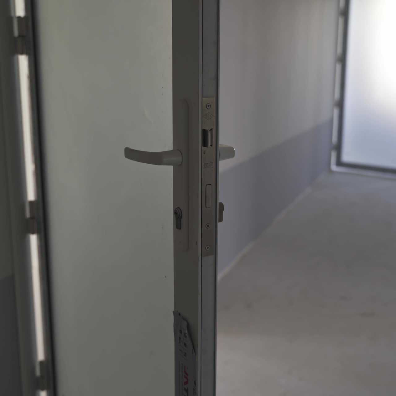 White corridor in a newly-built building. Focus on the unfinished pieces of ceiling cover. Open doors lock close up