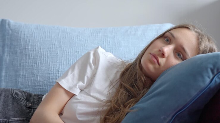 Tired woman falling asleep in the couch while watching tv