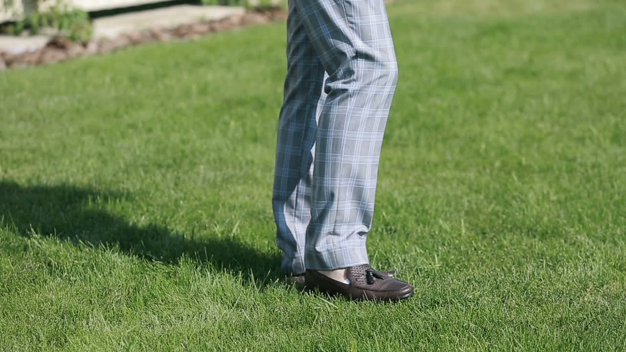 Elegant Male Shoes walking on green park grass.