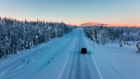 aerial view following a suv driving on a snowy road, in arctic wilderness of lapland