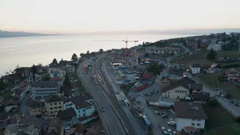 Luftaufnahme-Eines-Großen-Krans-Auf-Einer-Baustelle-In-Einer-Kleinen-Stadt-In-Der-Nähe-Eines-Schönen-Sees