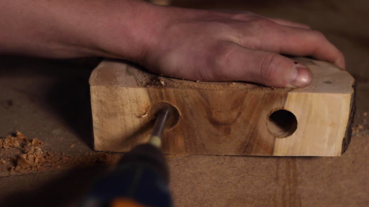 taladro de broca en v perforando un agujero en una pieza de decoración de madera cruda, primer plano