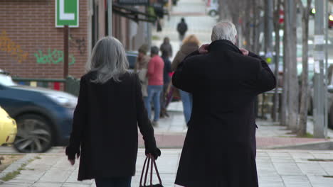 elderly couple walking down city street
