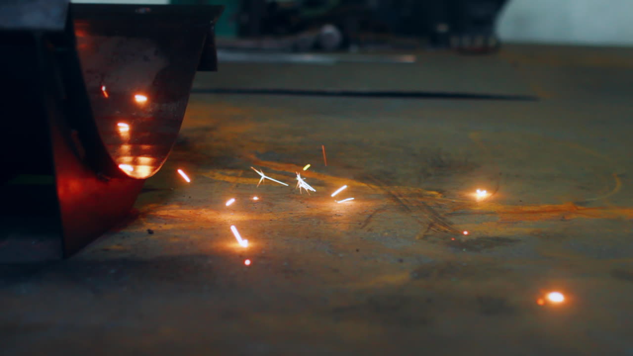 Metal welding process at factory. Close up bright metal sparks falling to floor