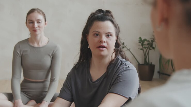 Young Woman With Down Syndrome Talking To Coach At Group Yoga Class
