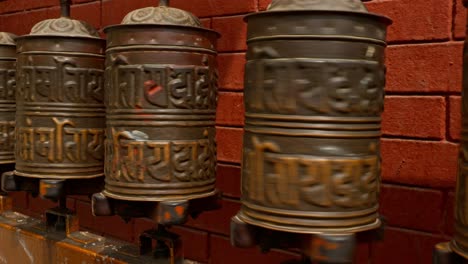 Close-up-of-person-with-tattooed-arm-spinning-Buddhist-prayer-wheels-at-temple