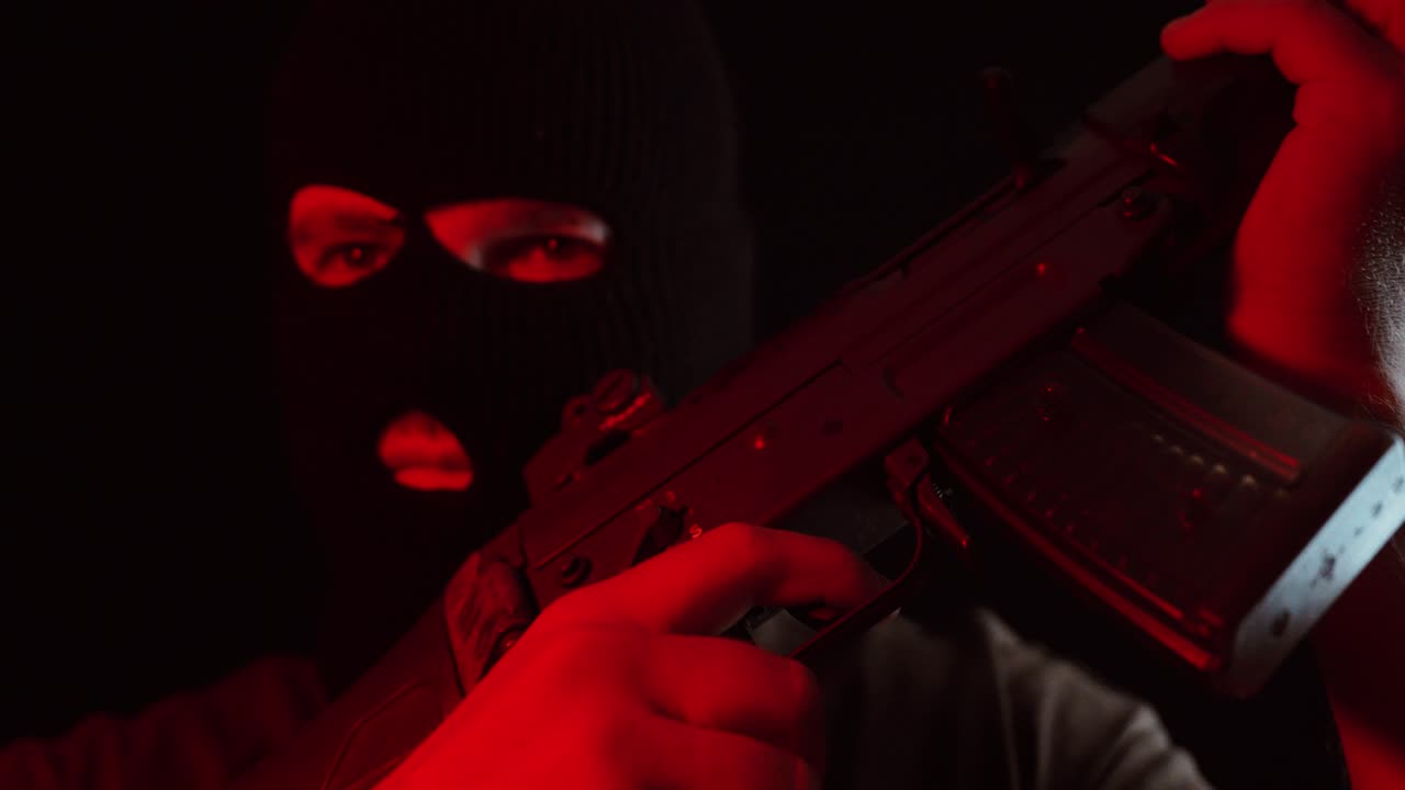 A masked figure holds a rifle under intense red lighting in a dark cinematic setting, symbolizing suspense, power, and tension in a dramatic film atmosphere