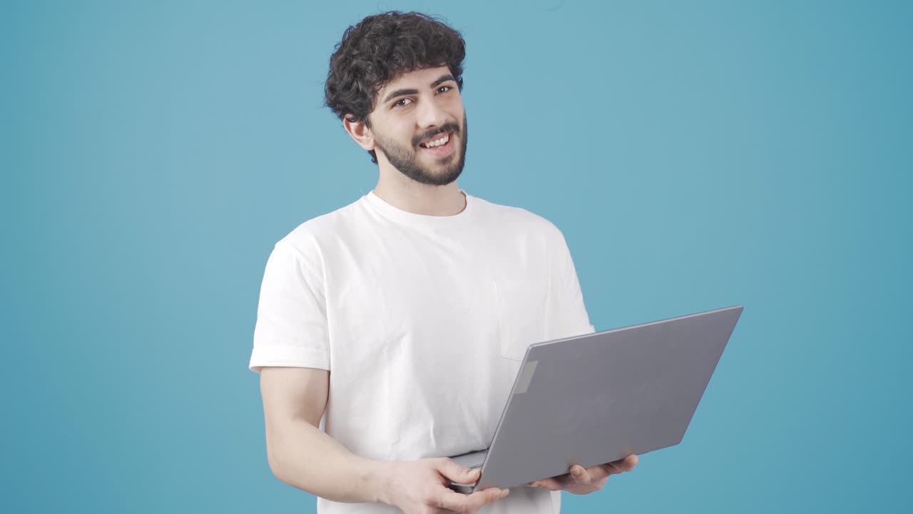 joven mirando la pantalla de la computadora portátil y haciendo una marca de verificación mirando a la cámara.