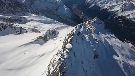 Luftaufnahme-Eines-Schneebedeckten-Bergrückens-Mit-Steilen-Klippen-Vor-Einer-Talkulisse