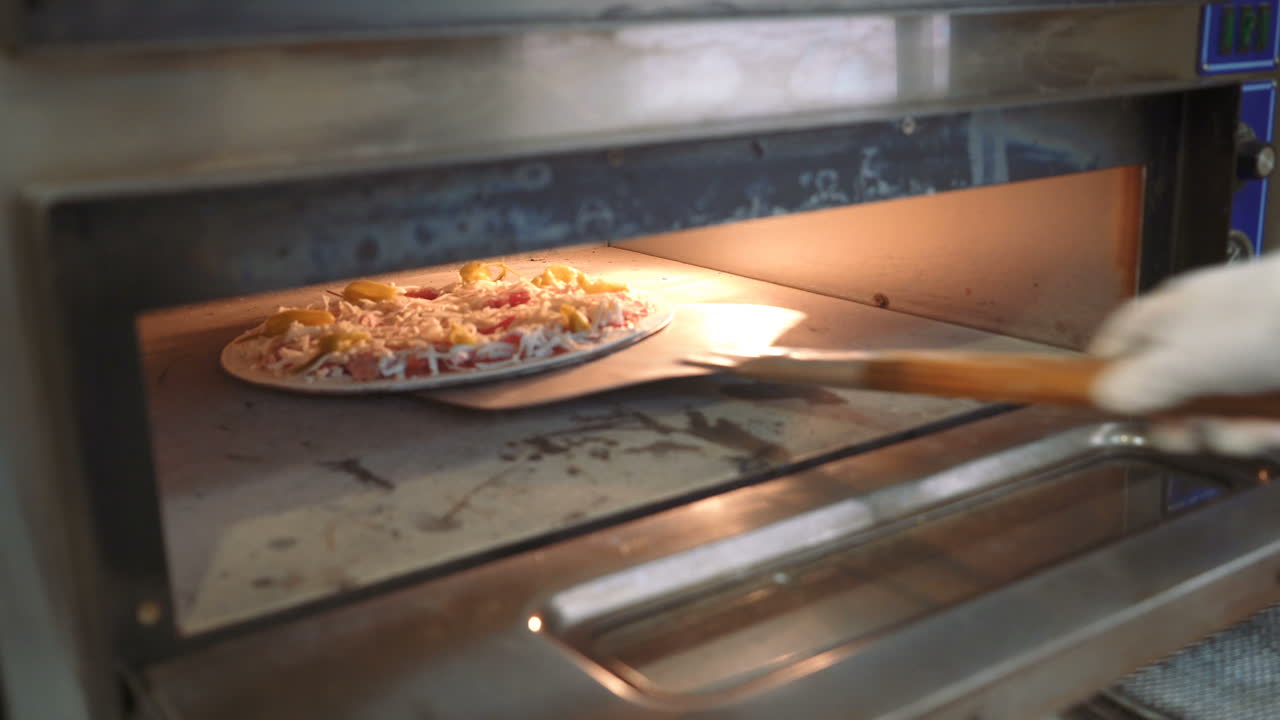 Process of making a pizza. Chef introducing a pizza in a hot oven in a restaurant kitchen.